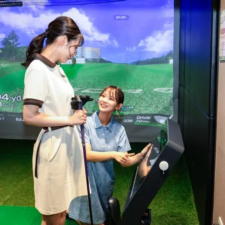 インストラクターとゴルフを楽しむ女性